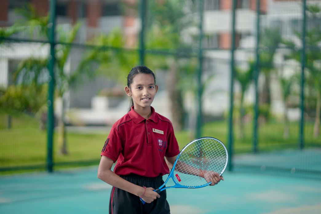Student holding a racquet on the school tennis court