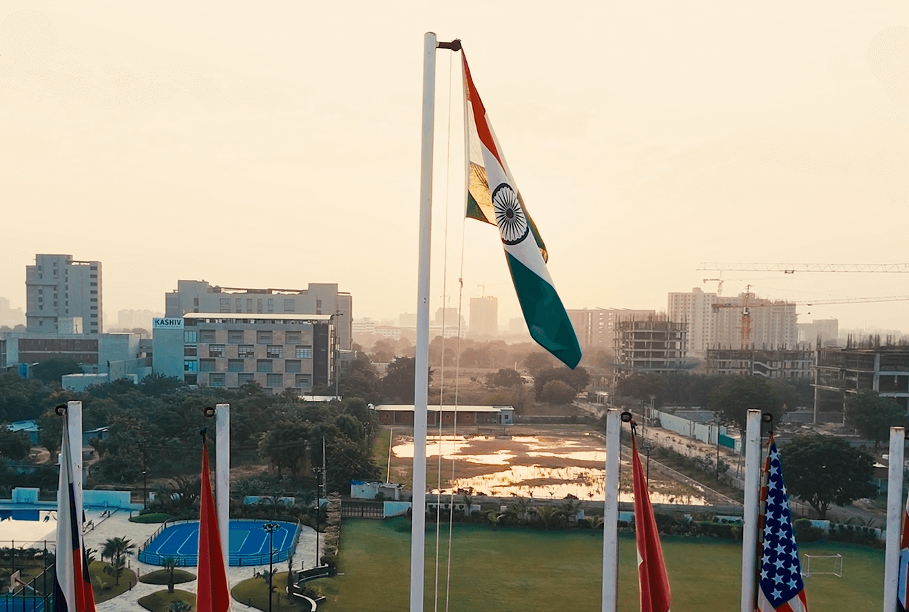 Indian and international flags flying over the Geneva Liberal School campus at sunrise
