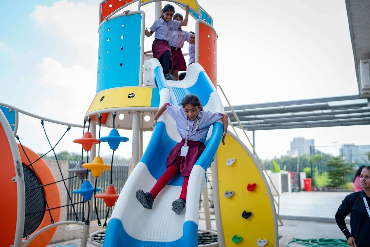 Students playing on the outdoor playground slide