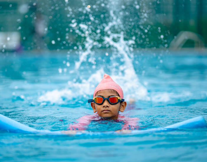 Student swimming with a cap and goggles in the school pool