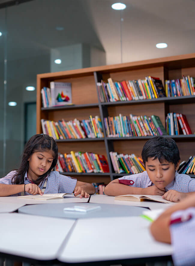Two students reading books in the school library