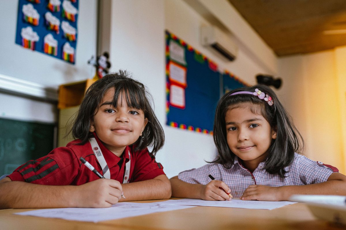 Two young students writing at their desks in class