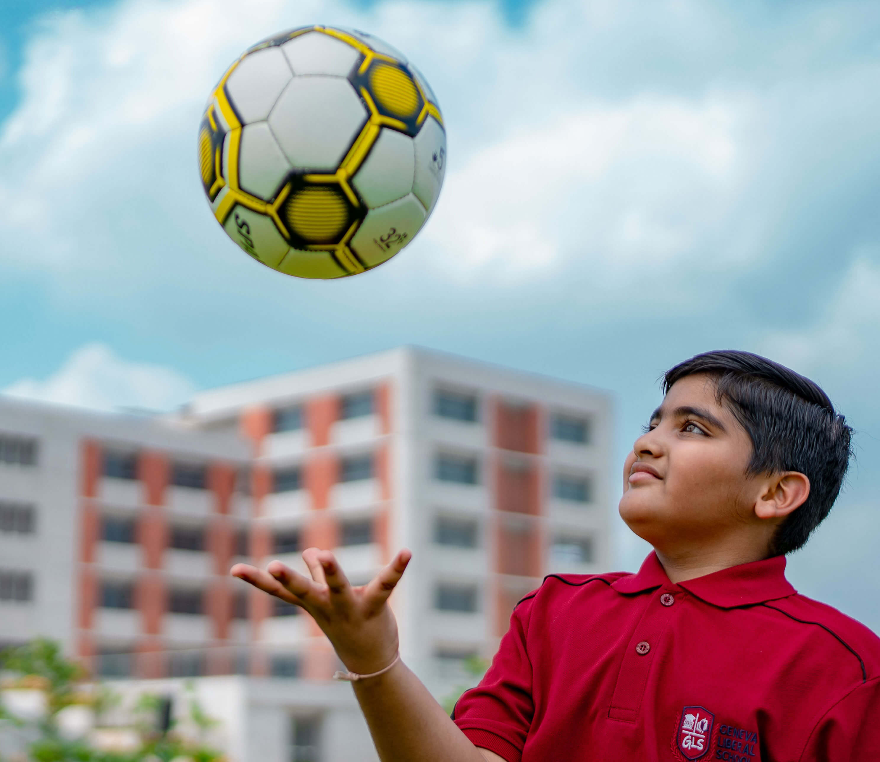 Student tossing a football in the air on the school ground